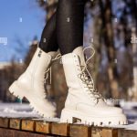 Femme en bottes blanches tendance sur neige blanche, gros plan. Jambes pour Femme dans des bottes en cuir d'hiver élégantes Photo Stock Alamy